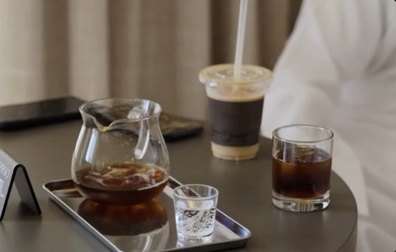 A V60 pour-over served on a tray with a carafe and small glasses
