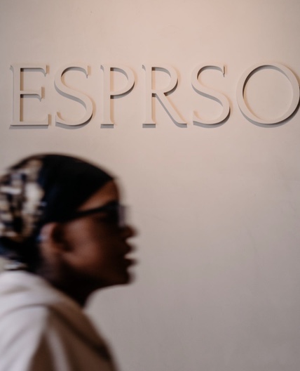 The ESPRSO sign on the shop wall, a customer passing in front